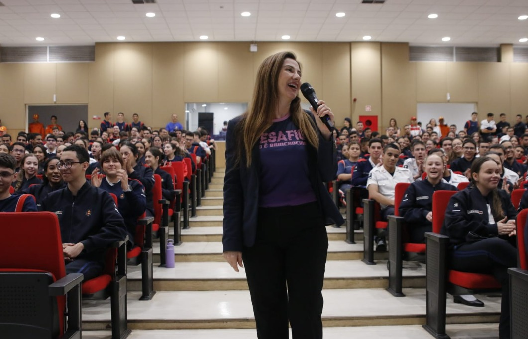 Sandra Faraj com microfone em auditório cheio durante palestra